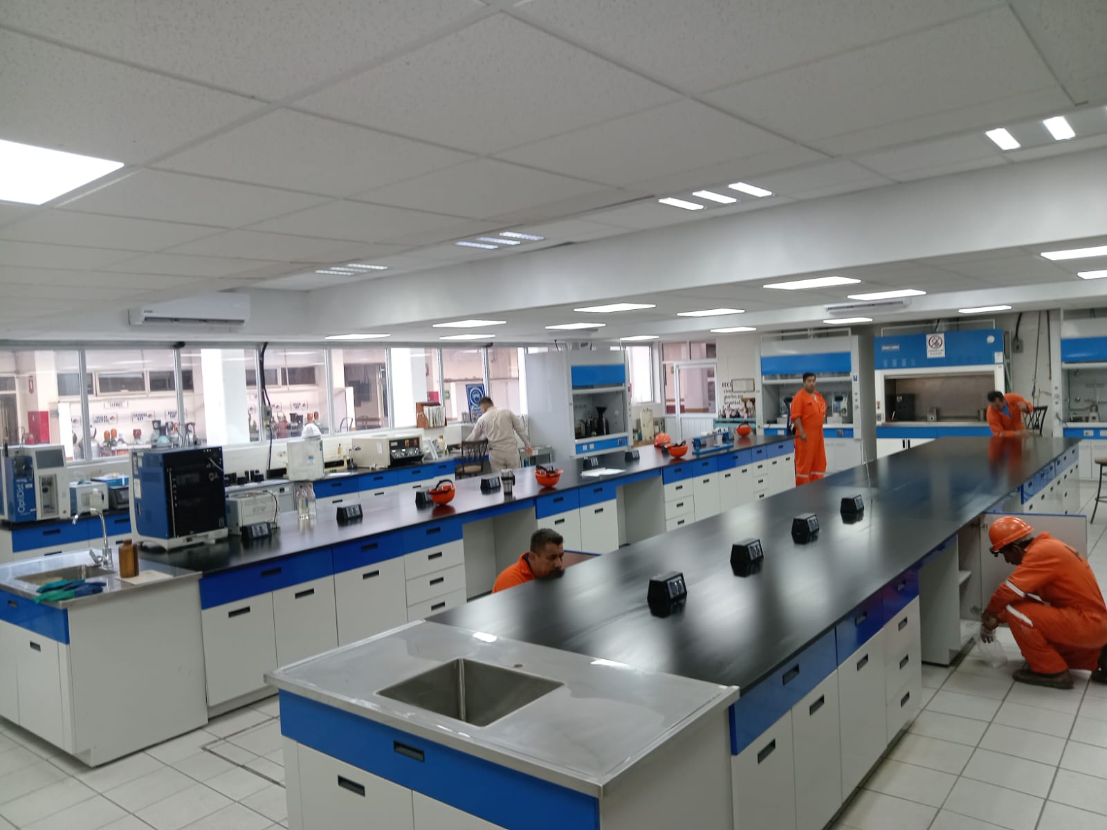 Laboratorio Pemex: sala amplia con mesadas paralelas y personal en área industrial