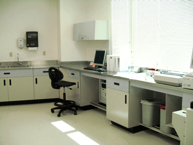 Mobiliario para laboratorio hospitalario con gabinetes azules soportando analizadores clínicos y equipo de diagnóstico.