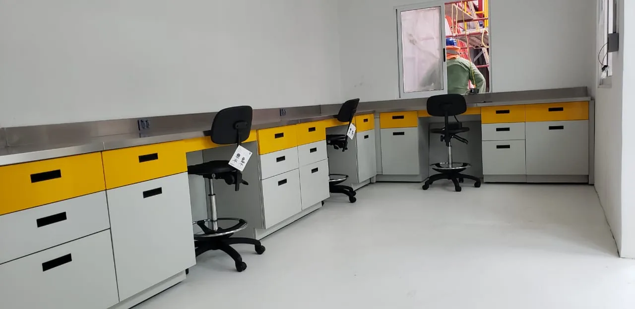 Vista del laboratorio con estaciones en U y actividad al fondo.