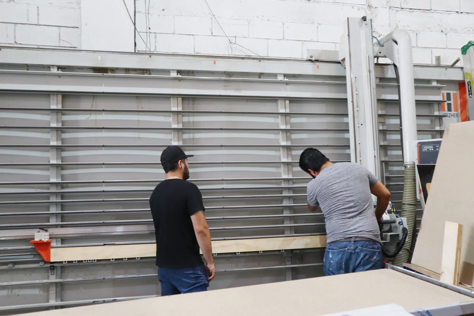 Dos operadores con cortadora vertical HOLZHER para cubiertas y paneles.
