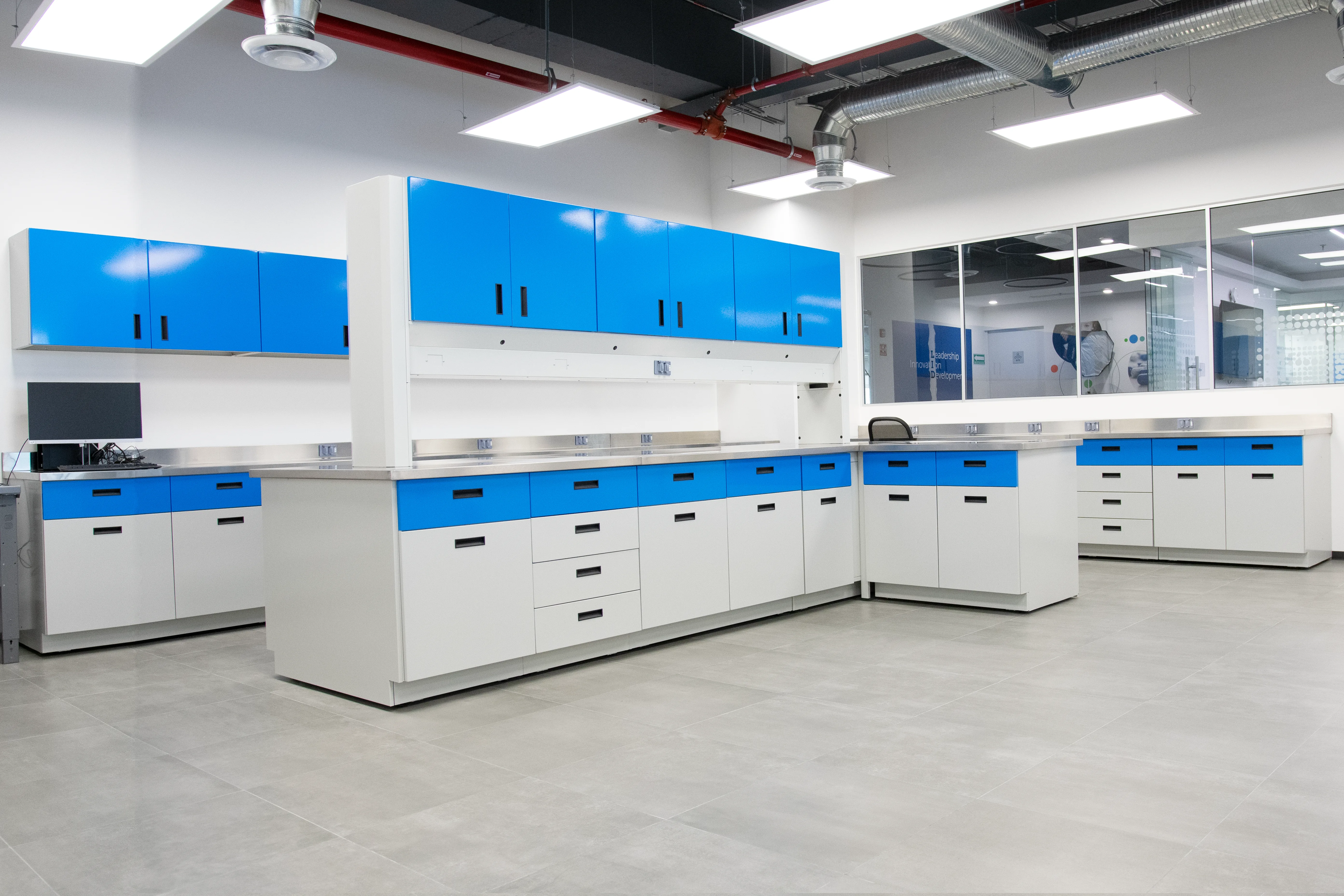 Zona 1 de trabajo general: mesas de laboratorio a muro con gabinetes y cubierta técnica