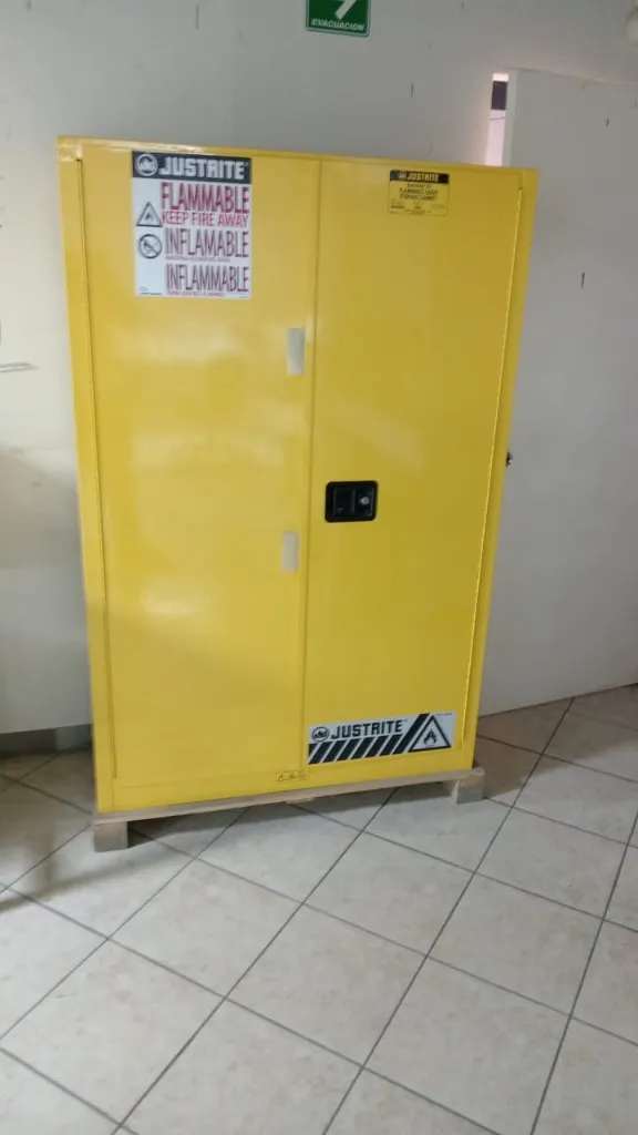 Gabinete de seguridad Justrite amarillo cerrado con etiquetas FLAMMABLE KEEP FIRE AWAY e INFLAMABLE