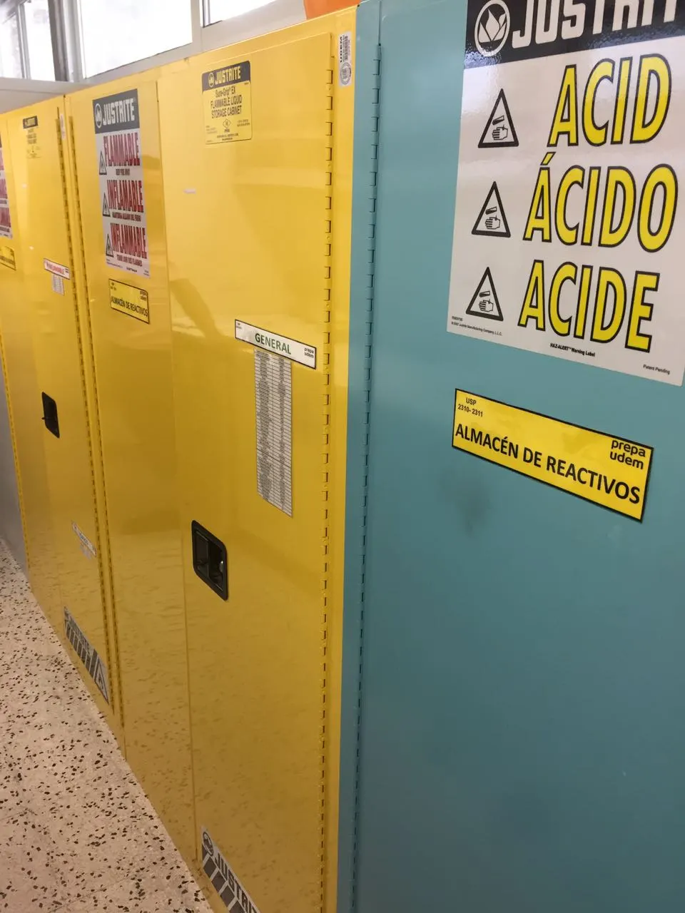Gabinetes de seguridad amarillos para inflamables y gabinete azul para ácidos en almacén de reactivos de laboratorio