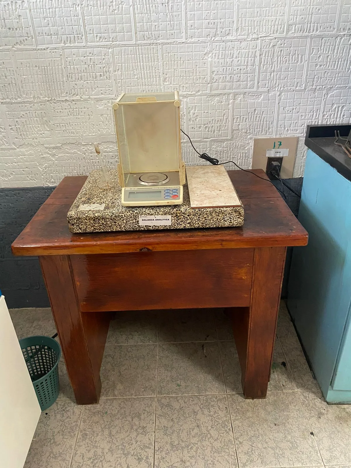 Mesa de madera con losa de granito usada como estación improvisada de balanza analítica